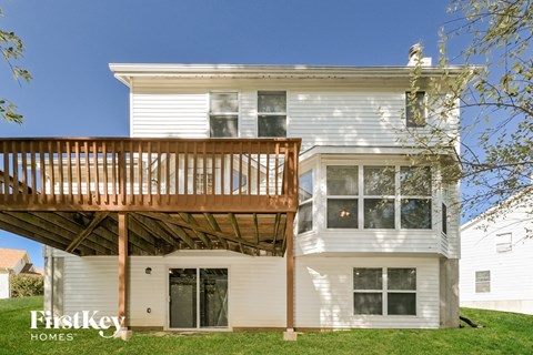 A white house with a wooden deck attached to it.