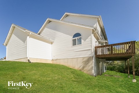 A house with a white siding and a wooden deck.