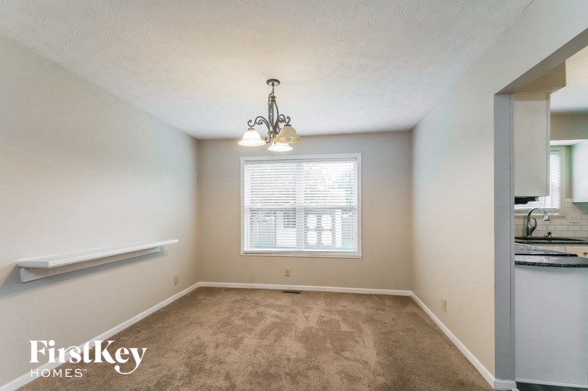an empty living room with a large window and carpet