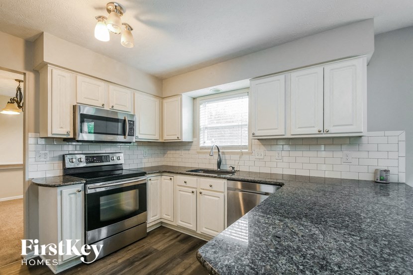 a kitchen with granite counter tops and white cabinets