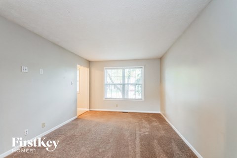 a spacious living room with carpet and a window