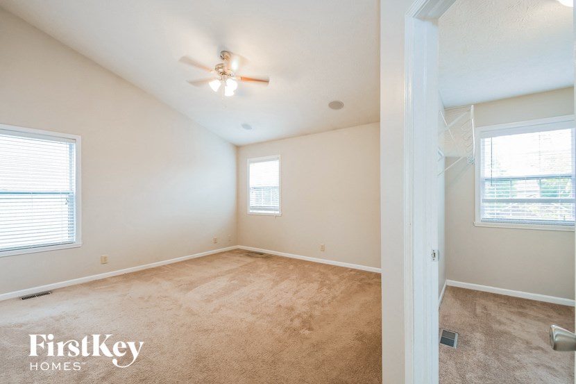 an empty room with a ceiling fan and two windows