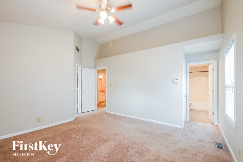 an empty living room with a ceiling fan and white walls