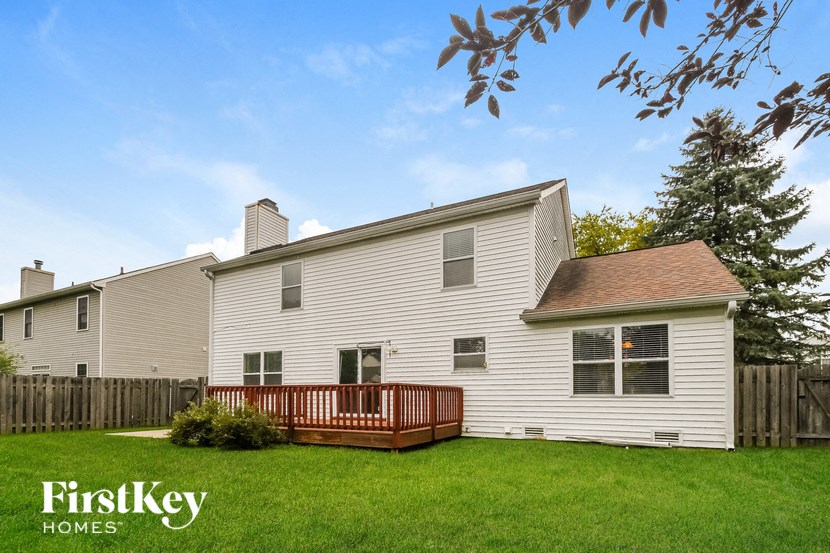 a white house with a wooden deck in a yard