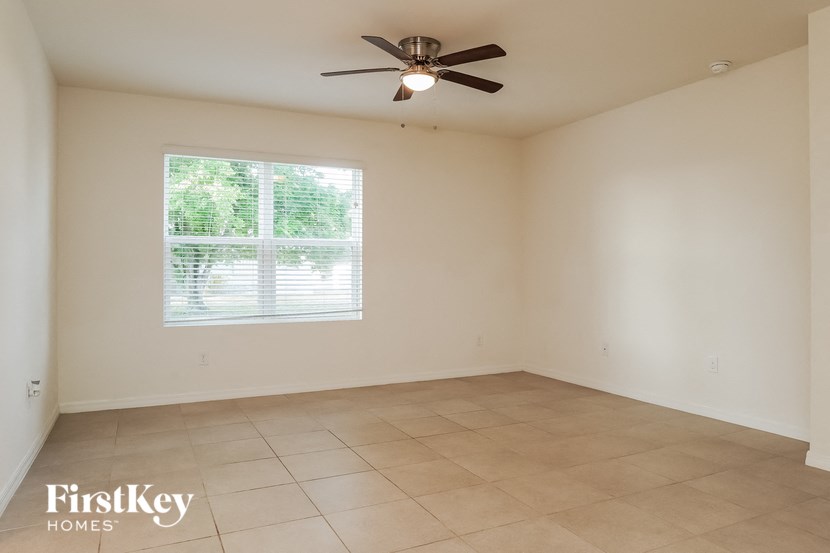 A room with a ceiling fan and a window with blinds.