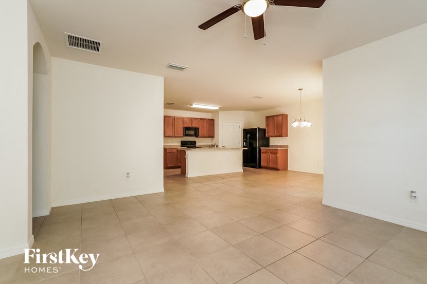 A spacious living room with a kitchen in the background.