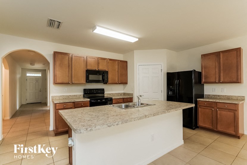 A kitchen with a black refrigerator and wooden cabinets.