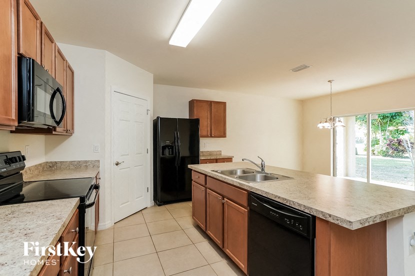 A kitchen with a black refrigerator and a white door.