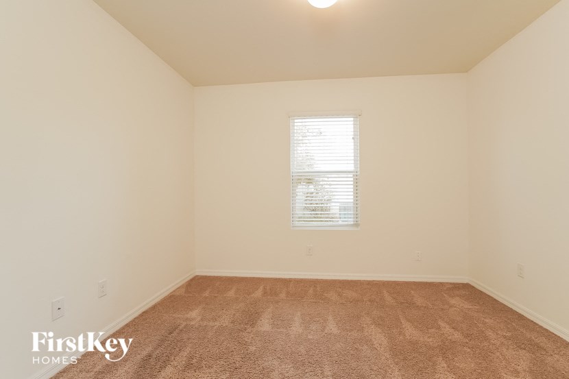 A room with a carpeted floor and a window with blinds.