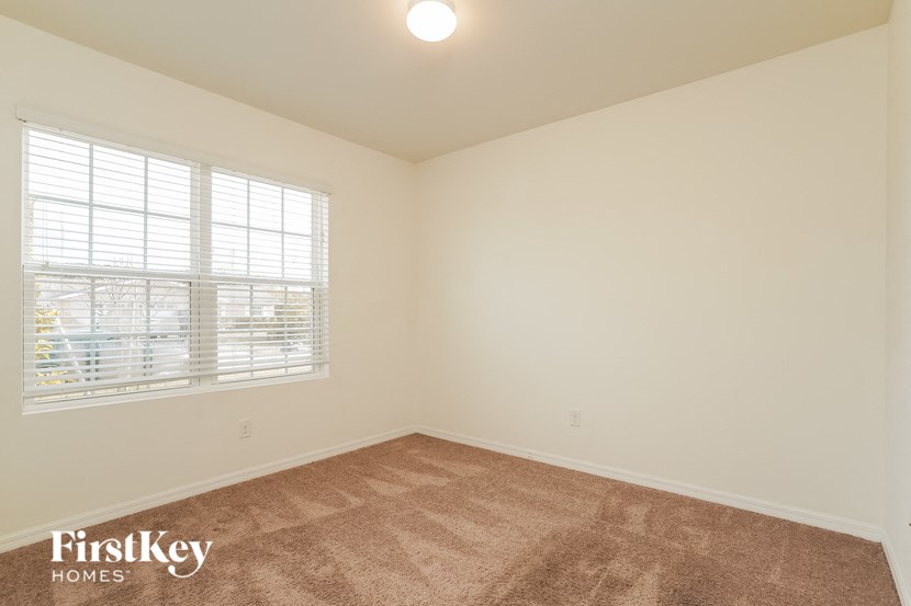 A room with a carpeted floor and a window with blinds.