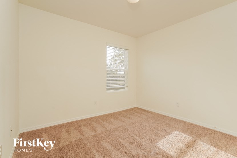 A carpeted room with a window and a FirstKey Homes logo.