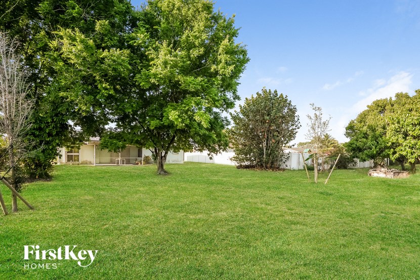 A lush green lawn with trees and a house in the background.