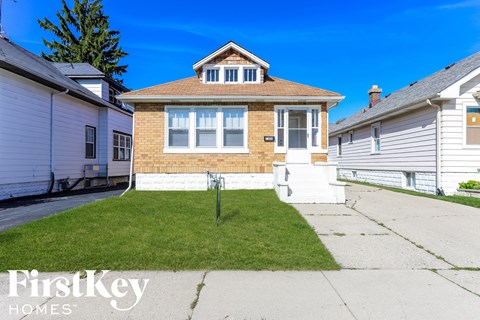 a brick house with a lawn in front of a sidewalk