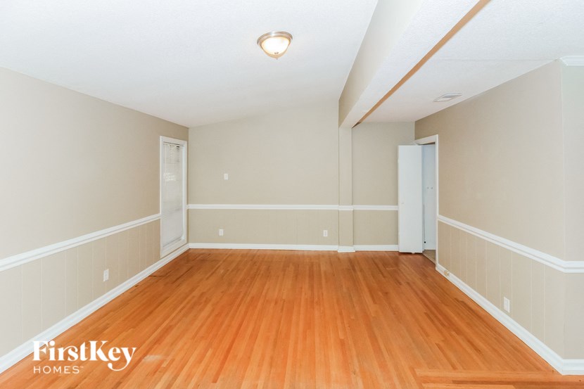 an empty living room with wood flooring and white walls