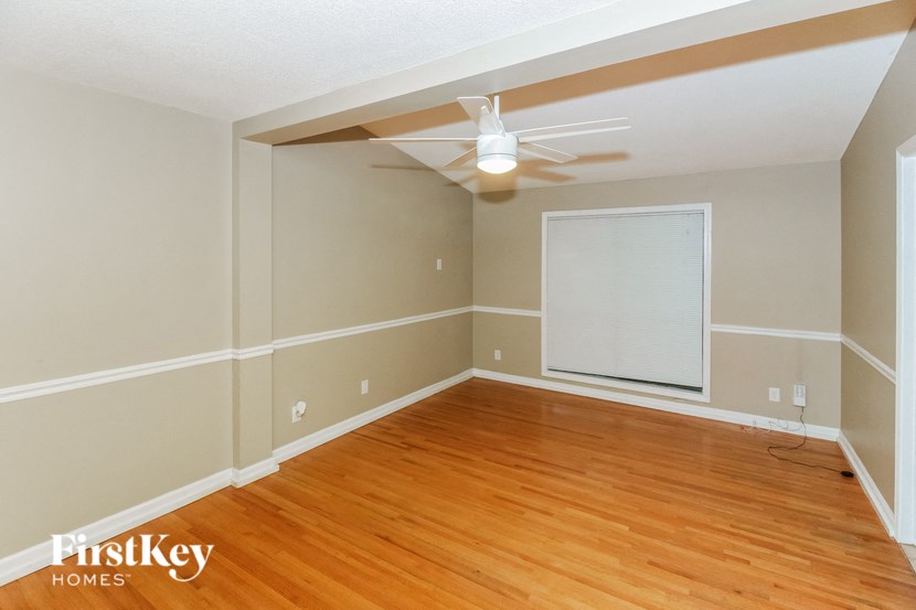 the living room with wood flooring and a ceiling fan