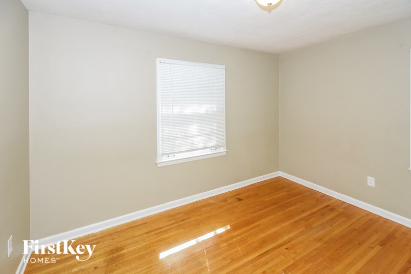 a bedroom with a wood floor and a window
