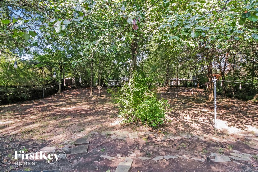 a backyard with trees and a fence and a bench