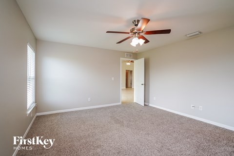 a spacious living room with carpet and a ceiling fan