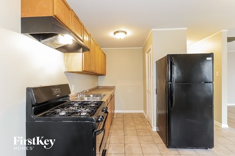 A black fridge and stove in a kitchen with wooden cabinets.