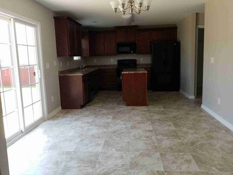 A kitchen with brown cabinets and a black refrigerator.