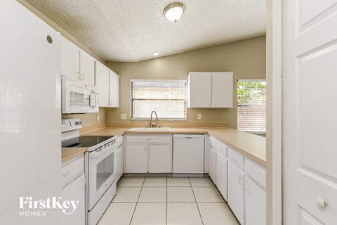 a kitchen with white cabinets and white appliances and white tiled floors