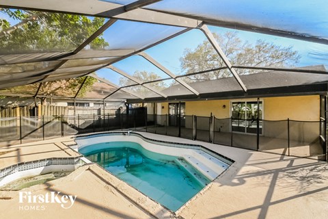 the pool and spa are under a patio roof with a pool