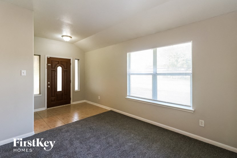 an empty living room with a large window and carpet