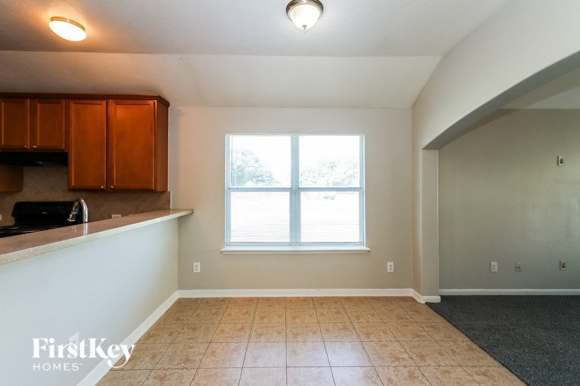 an empty living room with a window and a kitchen