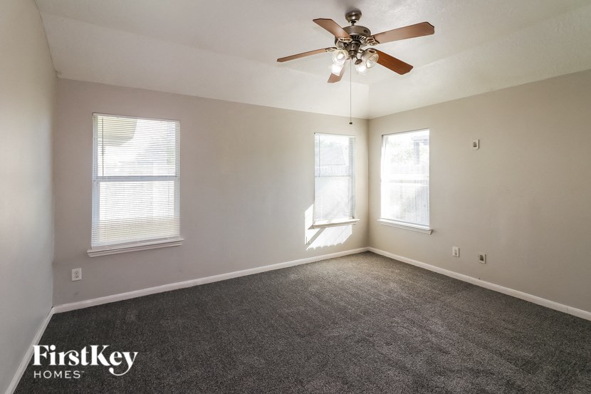 an empty room with a ceiling fan and two windows
