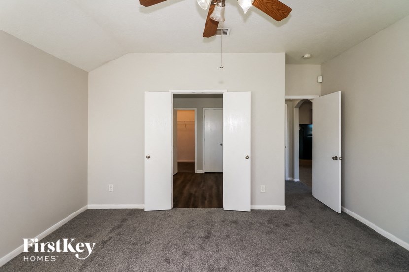 an empty living room with a ceiling fan and white doors