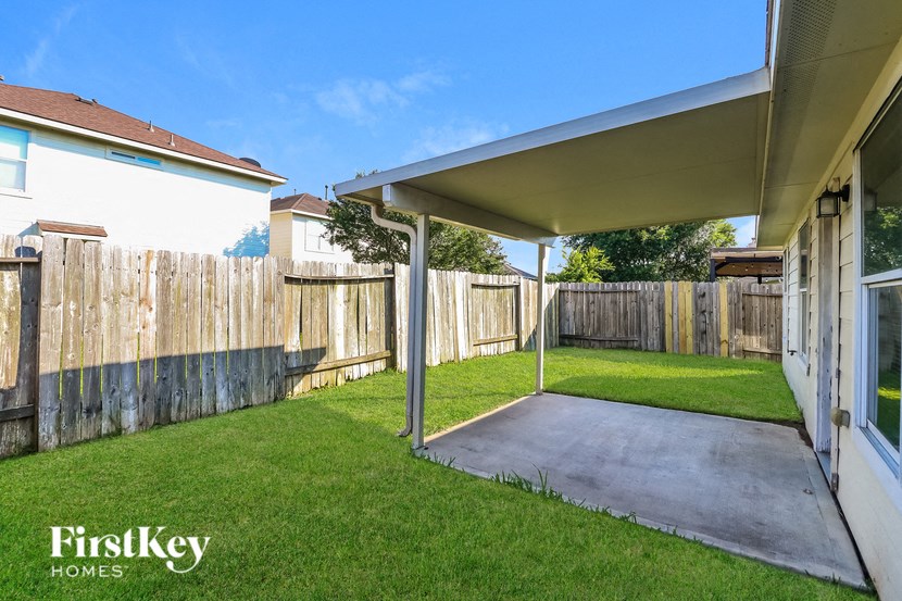 a patio in a backyard with a fence and grass
