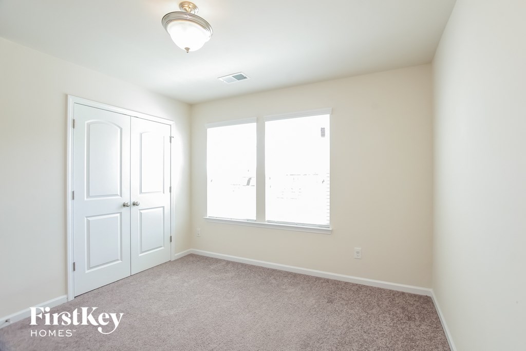a bedroom with two windows and a door and a carpeted floor