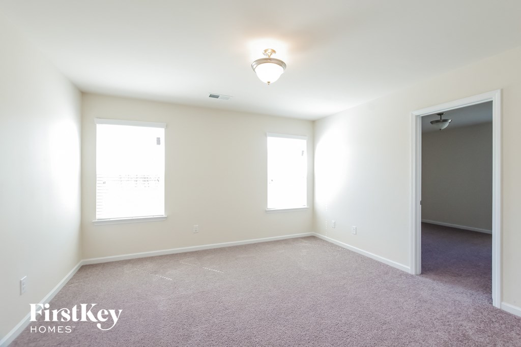 a bedroom with white walls and carpet and a door to a closet