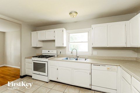 A kitchen with white cabinets and appliances.