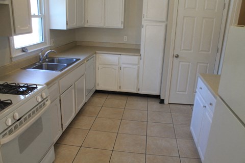 A kitchen with white cabinets and a tiled floor.