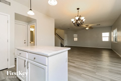 a kitchen and living room with white cabinets and a chandelier
