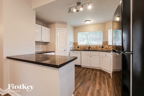 A kitchen with a black counter top and white cabinets.