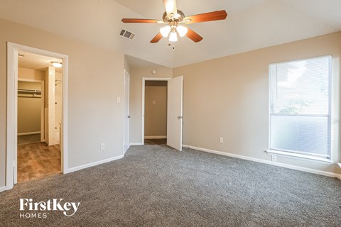 A spacious room with a ceiling fan and a window with blinds.