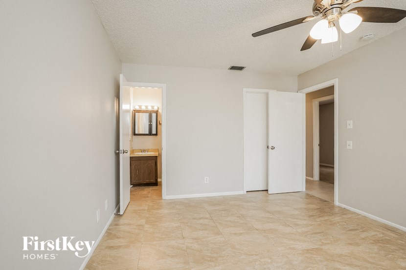 A spacious room with a ceiling fan and a door leading to another room.
