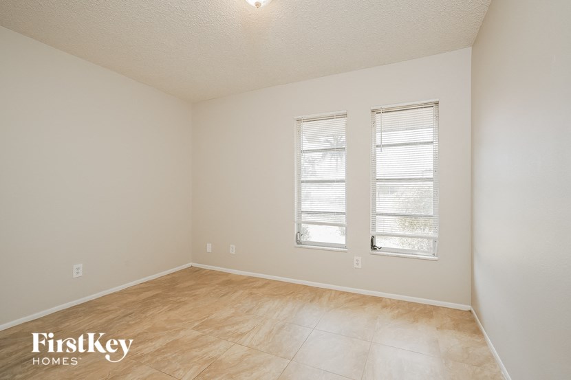 A room with wooden flooring and two windows.