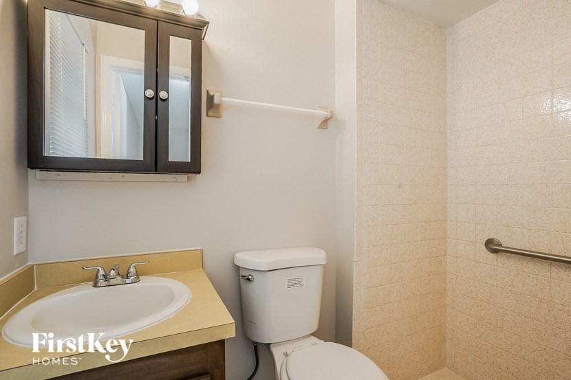 A bathroom with a toilet, sink, and medicine cabinet.