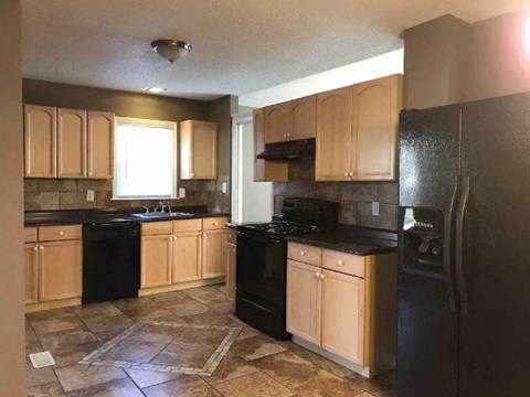 A kitchen with black appliances and wooden cabinets.