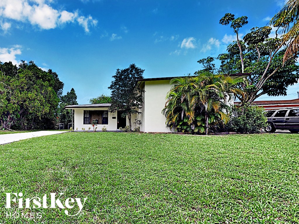 A house with a white exterior and a tree in front of it.