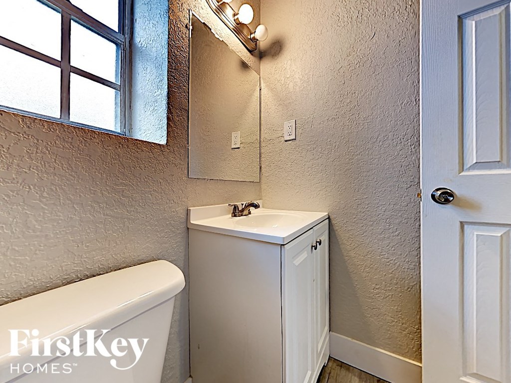 A small white bathroom with a tub, sink and a window.