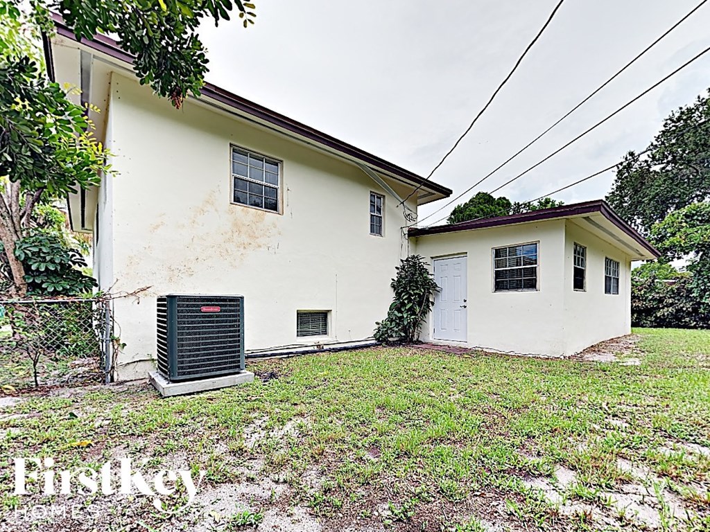 A white house with a black air conditioning unit in front.