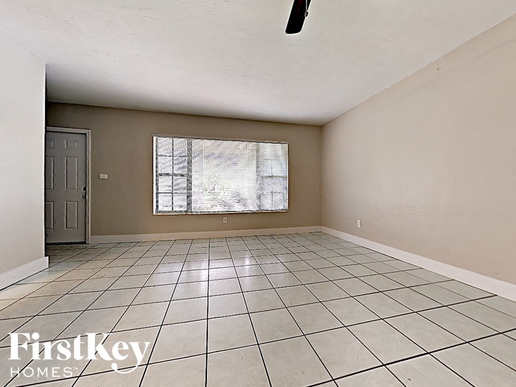 A room with a tiled floor and a window with a view of trees outside.