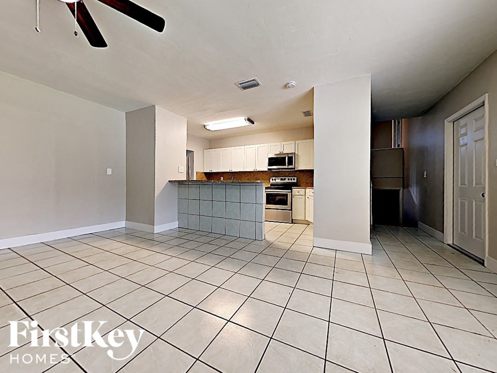 A spacious kitchen and living room with a tile floor and a ceiling fan.
