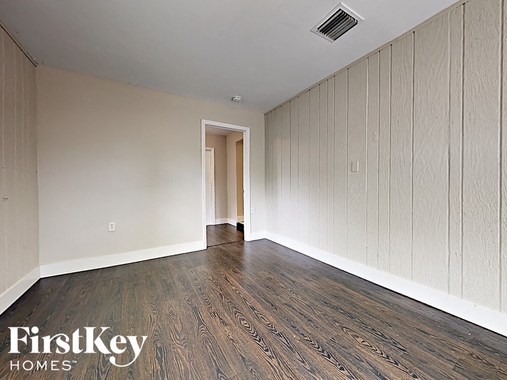 A room with wooden flooring and a doorway leading to another room.