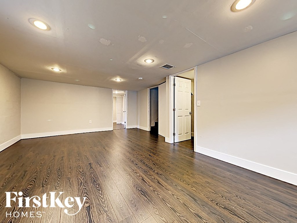 A spacious room with wooden flooring and a white ceiling with lights.