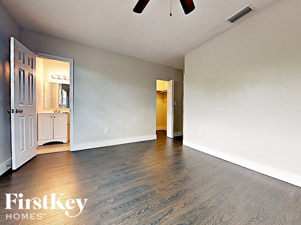 A room with a wooden floor and a white wall with a door on the right side.
